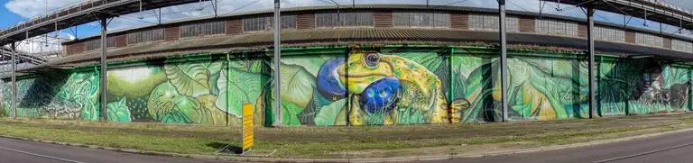 A huge piece of artwork along the corrugated fence of this industrial building in Val-de-la-Haye