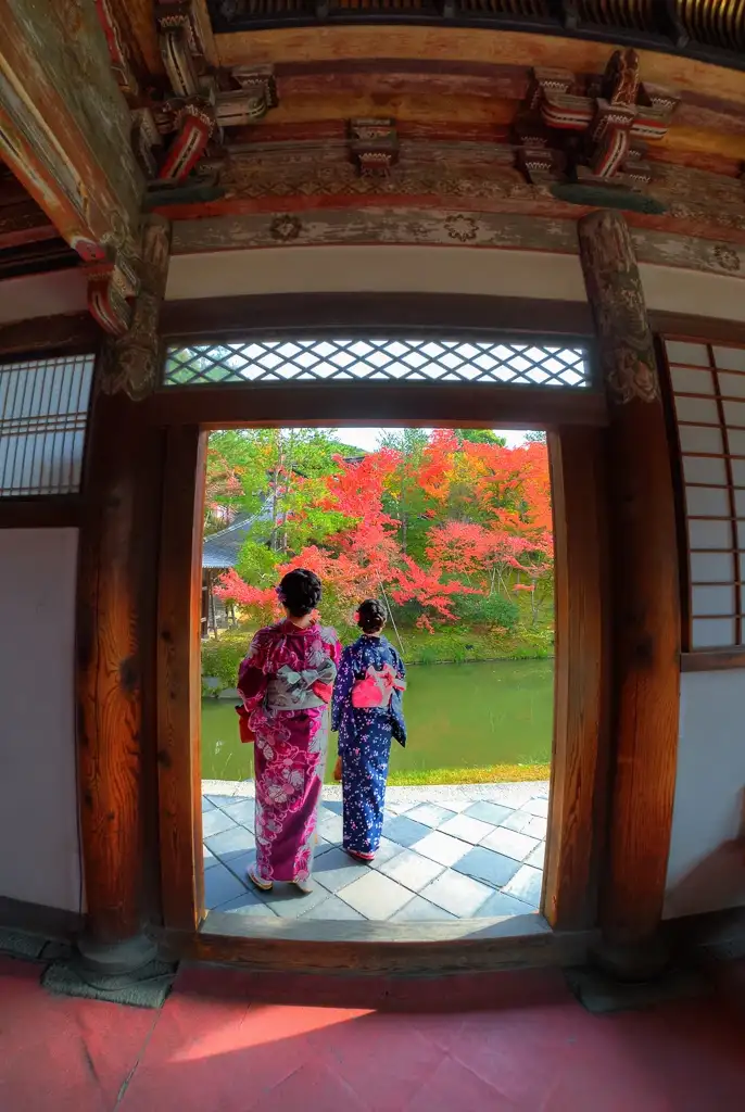  Two women in kimonos looking out onto the pond in the place of worship in autumn colors Kodai ji Kyoto