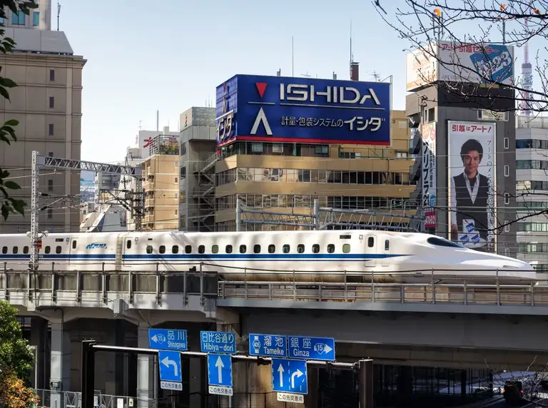 The N700 Shinkansen speeds over a bridge in a street scene Shiodome