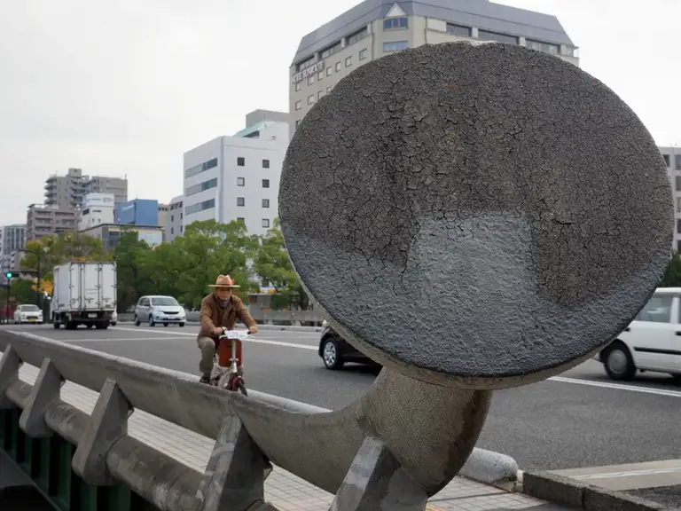 Japanese man in a hat rides a bike over Heiwao Bridge Hiroshima