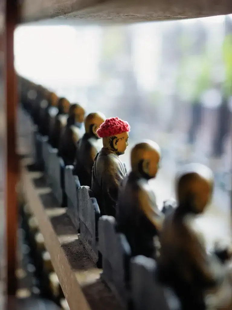  Row of Bronze Buddhist Monk figures one with a red knitted hat Daisho in Temple Miyajima Island